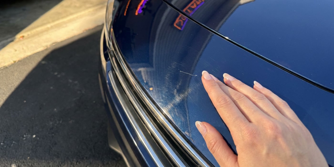 Close-up of light swirl marks and a small scuff on glossy car paint.